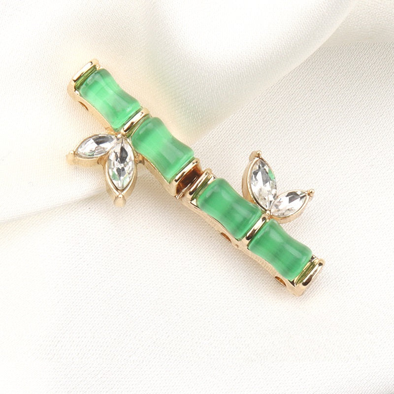 Botón verde estilo bambú con pedrería tipo diamante, resina y metal