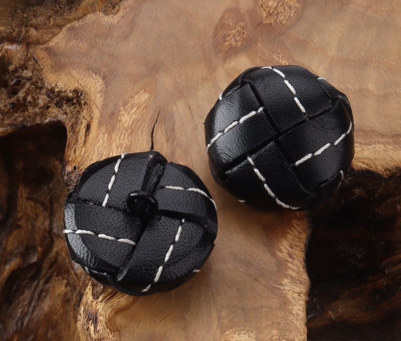Pair of black stitched leather football buttons with white stripe stitching