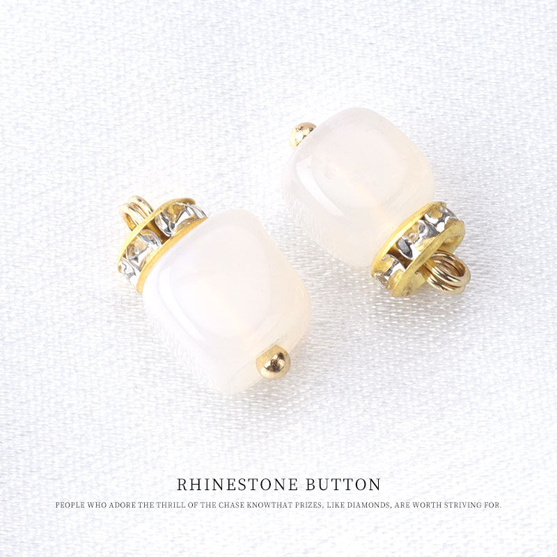 White natural stone frog knot button with gold tone loop and rhinestone accents