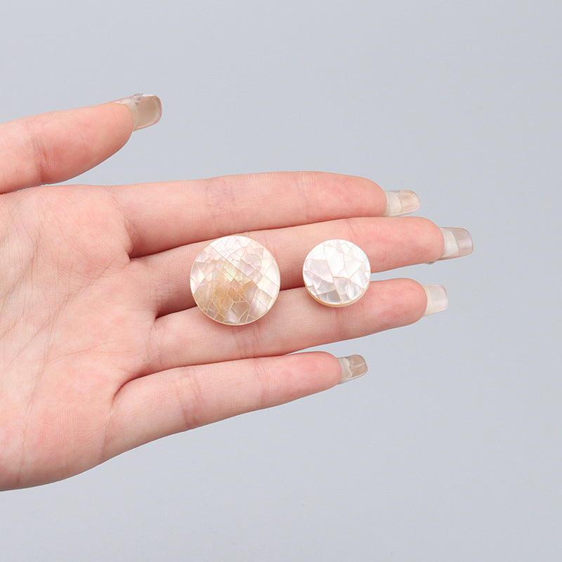 Set of 2 natural shell round buttons shown in hand, iridescent white-pink