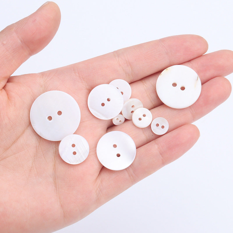 Pack of round white pearl buttons with two holes in hand