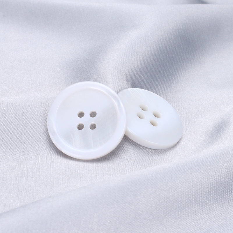 Pair of white 4-hole shirt buttons on fabric