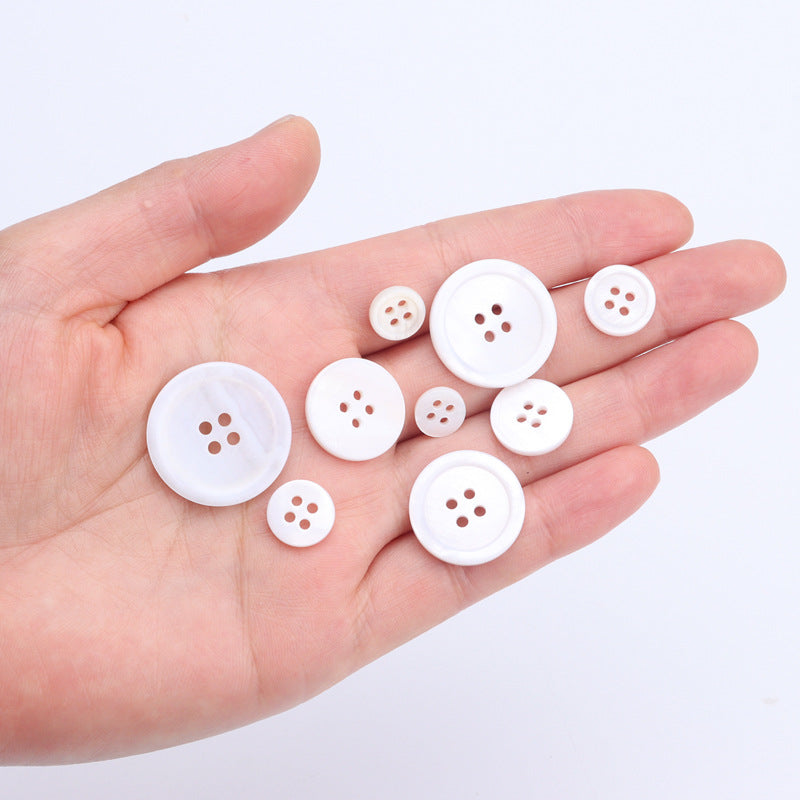 Set of white 4-hole buttons, various sizes, in hand
