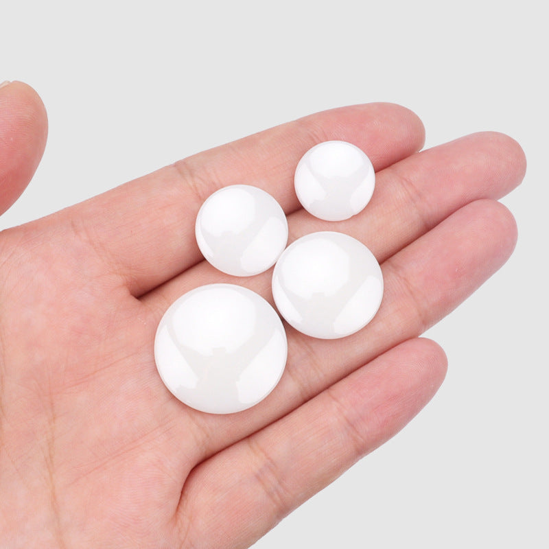 Set of five white spherical ceramic buttons with shank, in hand