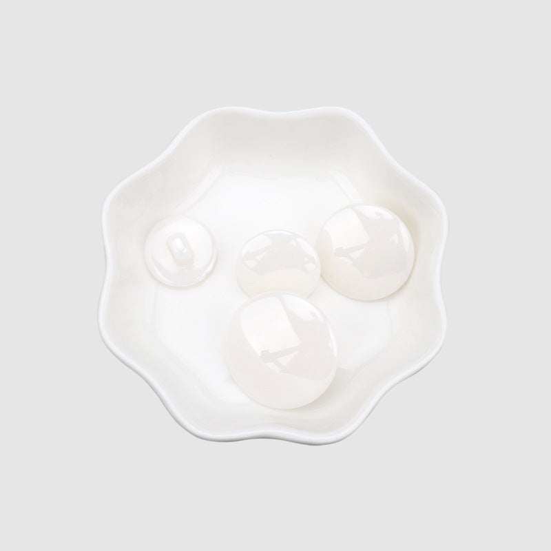 White spherical ceramic buttons set in a dish, shank backs visible