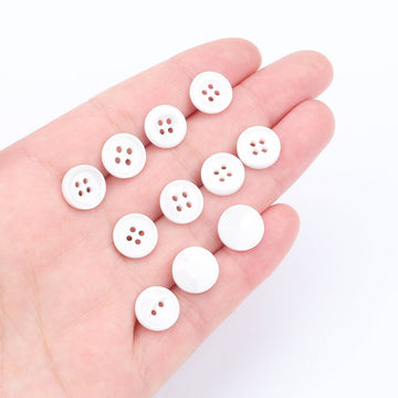 White ceramic shirt buttons, 4-hole design, shown on hand