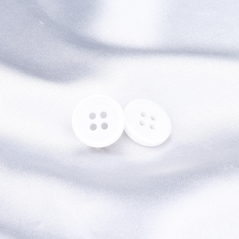 White ceramic buttons with 4 holes, close-up on light fabric