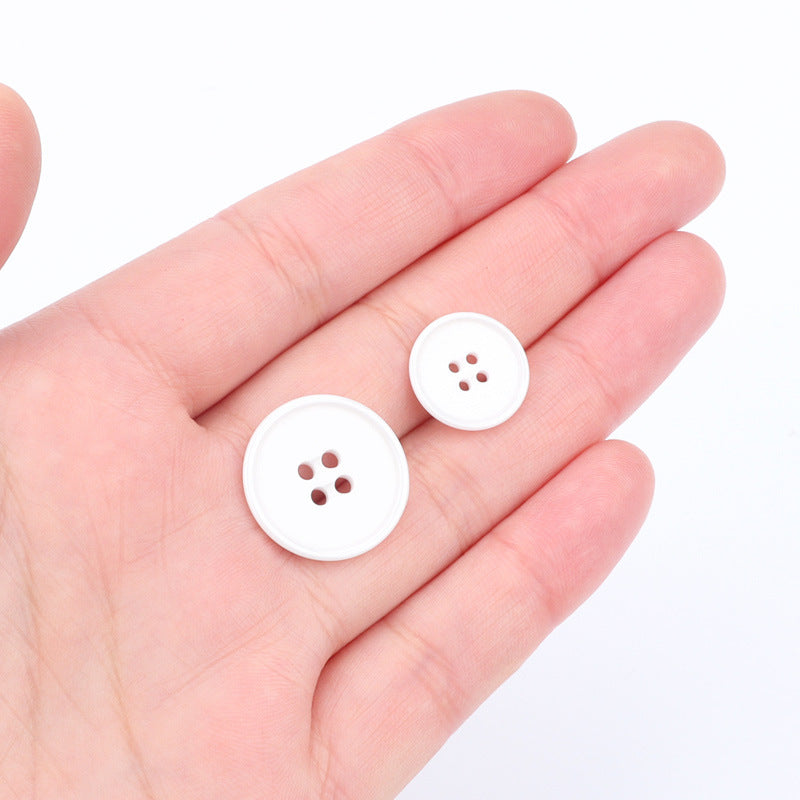 White 15mm/20mm ceramic suit buttons with 4 holes, shown in hand for scale
