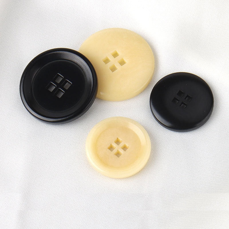 Set of beige and black corozo-style buttons with square-hole cross design