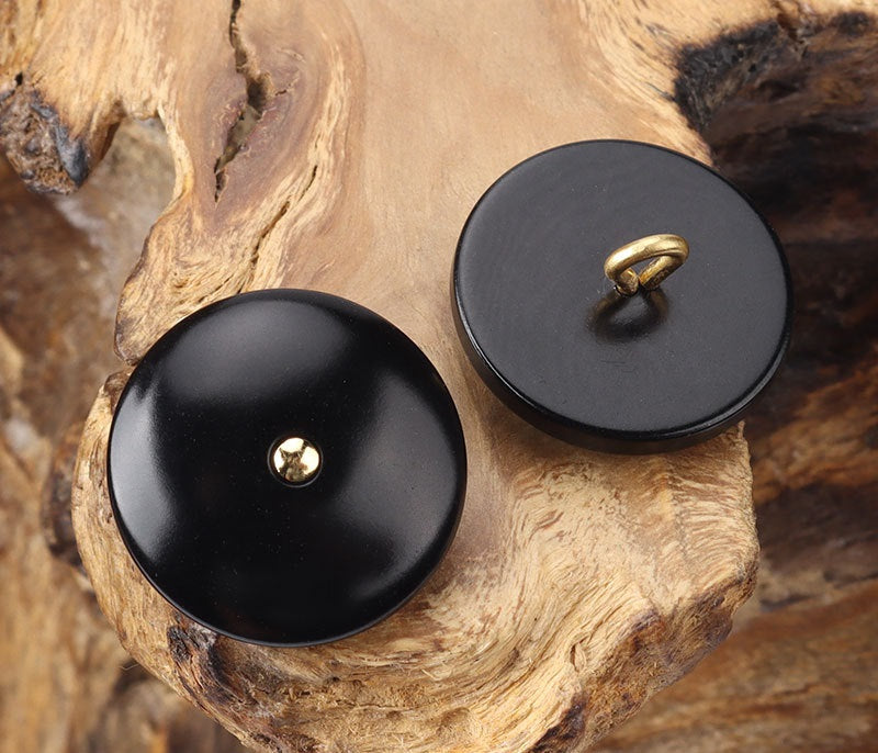 Round black corozo shank buttons with brass shank on the front