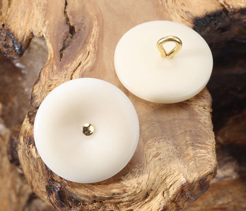 White/beige corozo buttons with gold-toned loop shanks, two round fronts