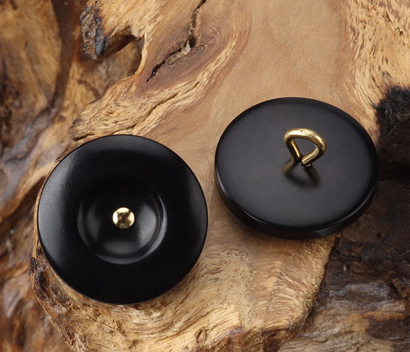 Black round corozo shank buttons with brass shank, pair close-up