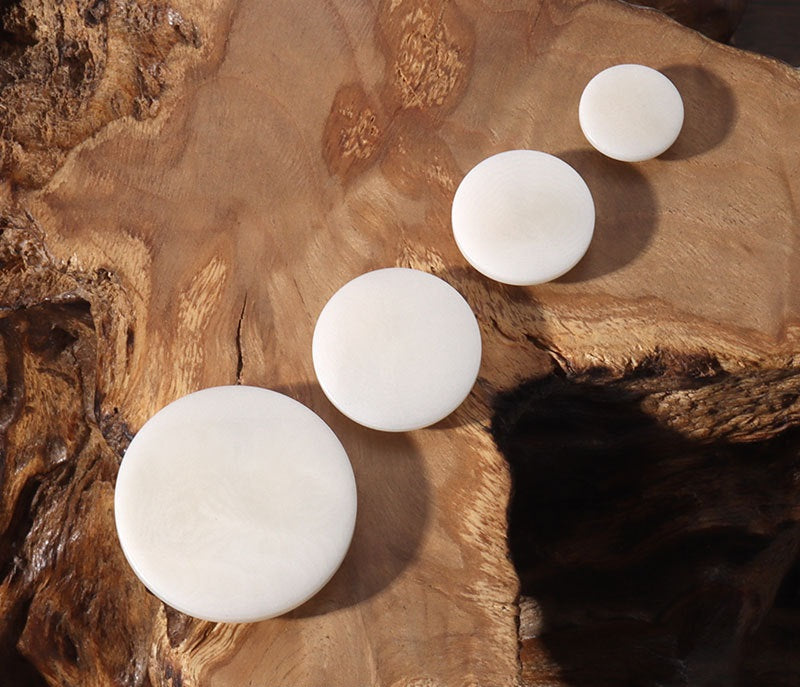 Set of round flat corozo buttons with concealed holes, light ivory tones
