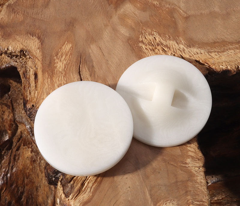 Two round flat corozo buttons with concealed hole details, light ivory