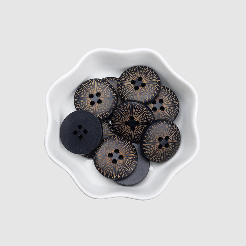 Bowl of round 4-hole dark wood buttons with gold sunburst radial laser pattern