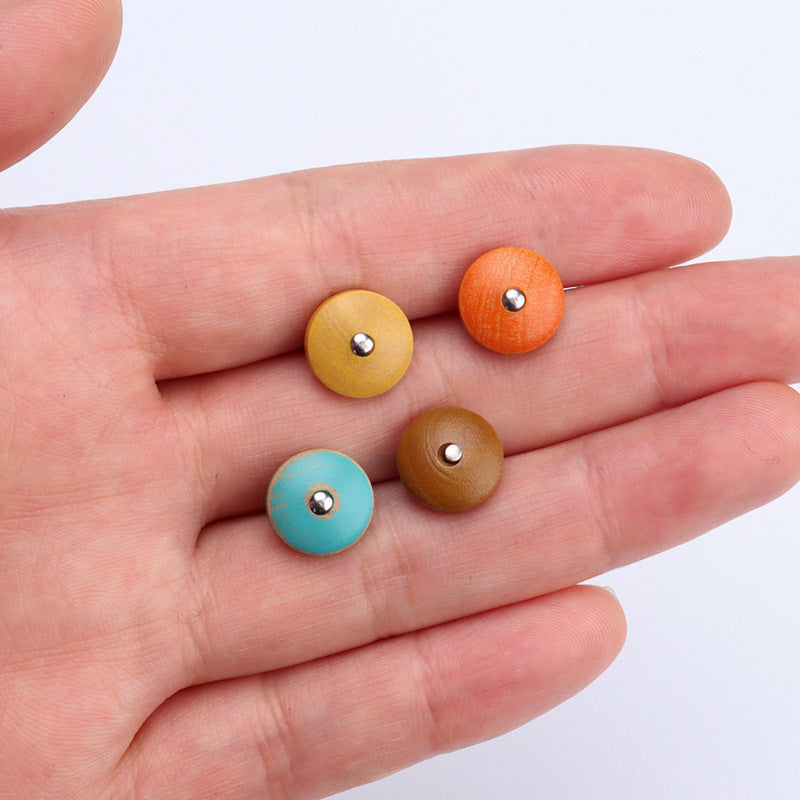 Set of round wood buttons in hand: yellow, orange, blue, and brown with metal shanks