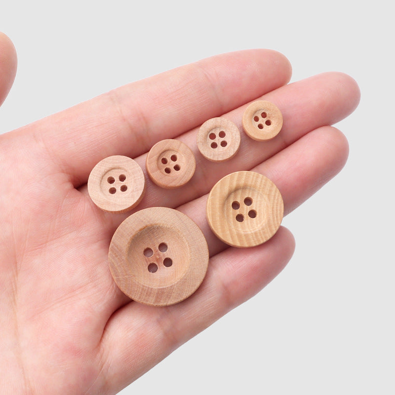 Natural camellia wood four-hole buttons in hand, wide rim (10–25mm)