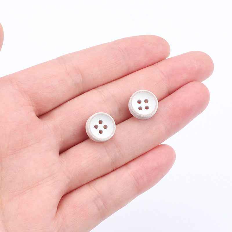 Two small round 4-hole white-painted wood buttons in hand
