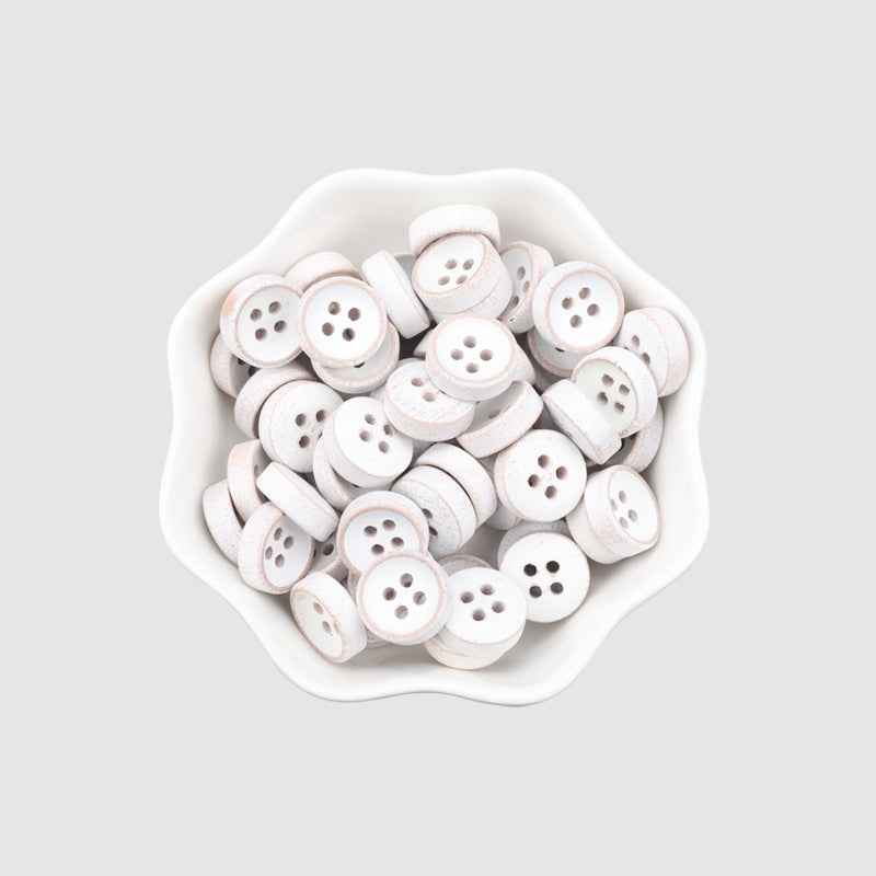 Pile of round 4-hole white-painted wood buttons in a small tray