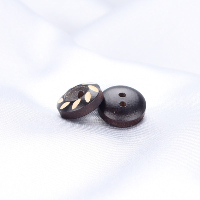 Pair of dark brown/black painted round wood buttons with leaf inlay and two holes