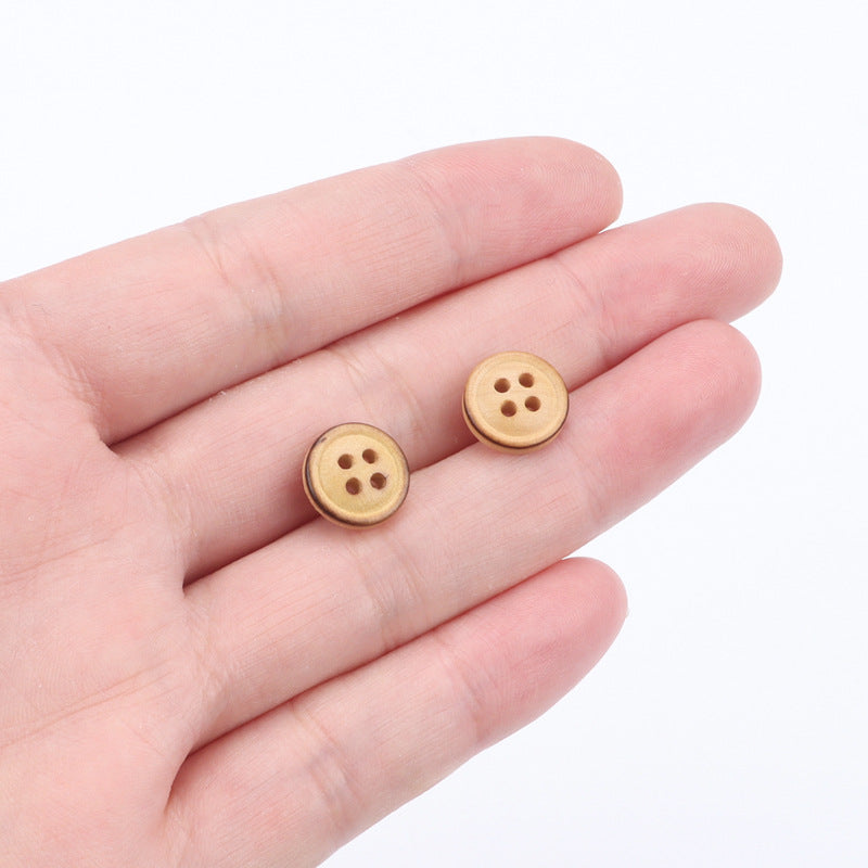 Pair of 11.5mm poplar wood four-hole buttons in hand with burned edge detail