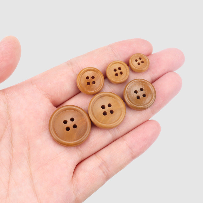 Set of round 4-hole poplar wood buttons in warm brown, held in hand.