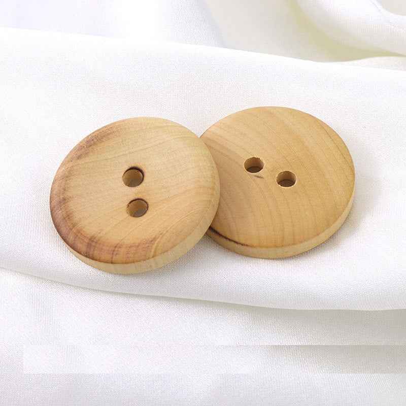 Two round 2-hole fire-burned boxwood buttons, light tan wood with carved holes.