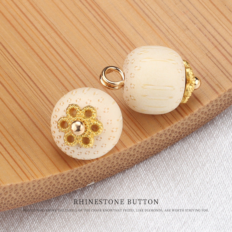 Cream bamboo frog knot button with gold flower setting and clear gem center, front view