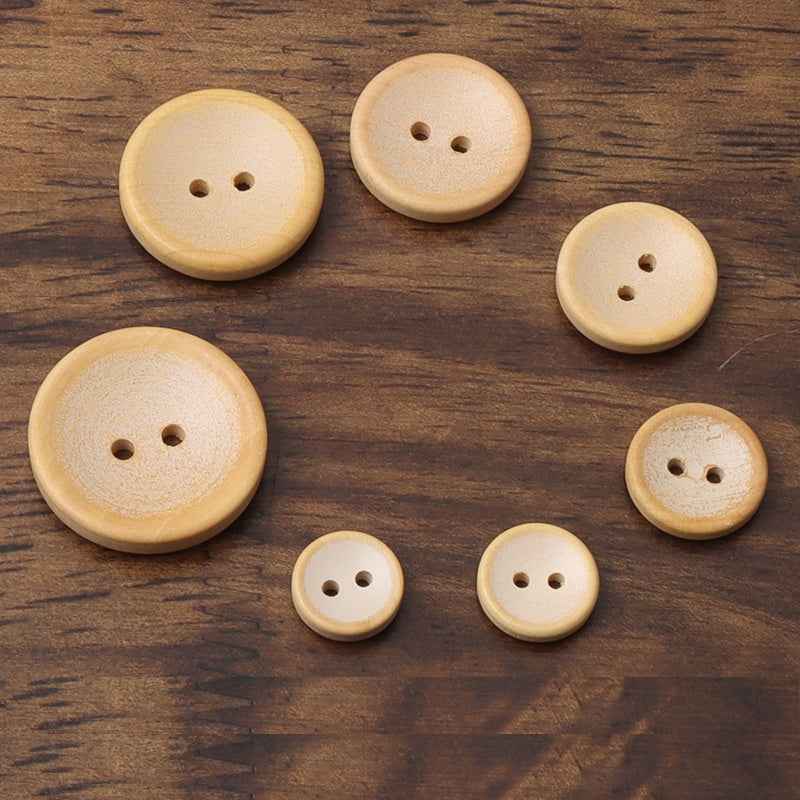 Assorted sizes of two-hole round wooden buttons in light tan with visible holes.