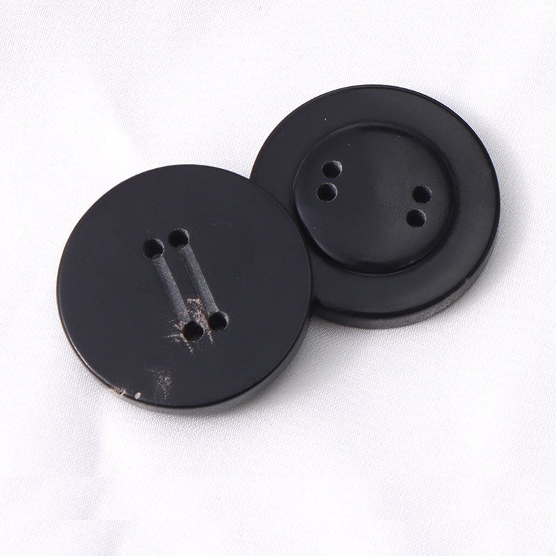 Two round black 4-hole horn buttons, double-groove shanks visible