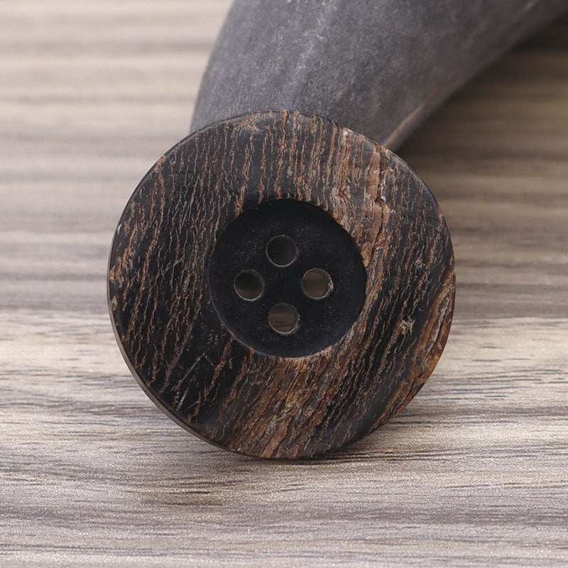 Close-up round 4-hole dark horn-look button with textured wide edge rim