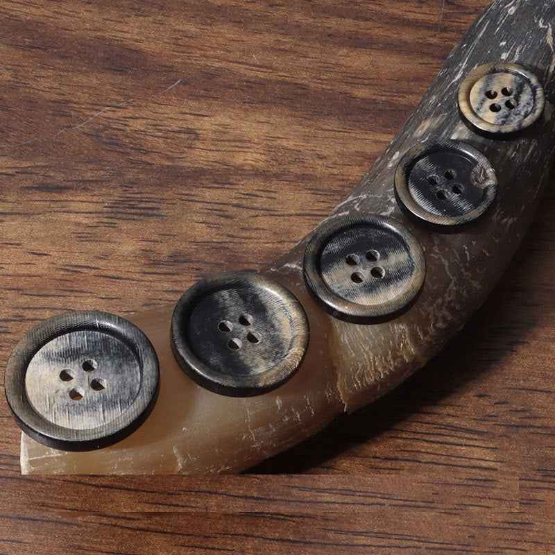 Dark buffalo horn buttons, round set with stitched-hole detail and textured edges