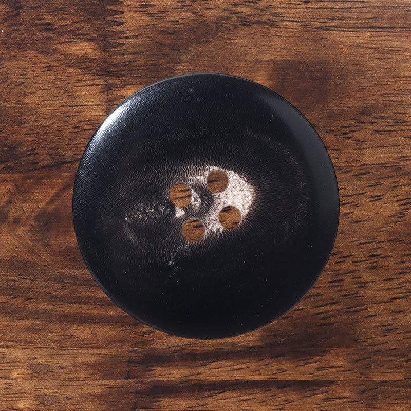 Black round four-hole button with horn-style border detail
