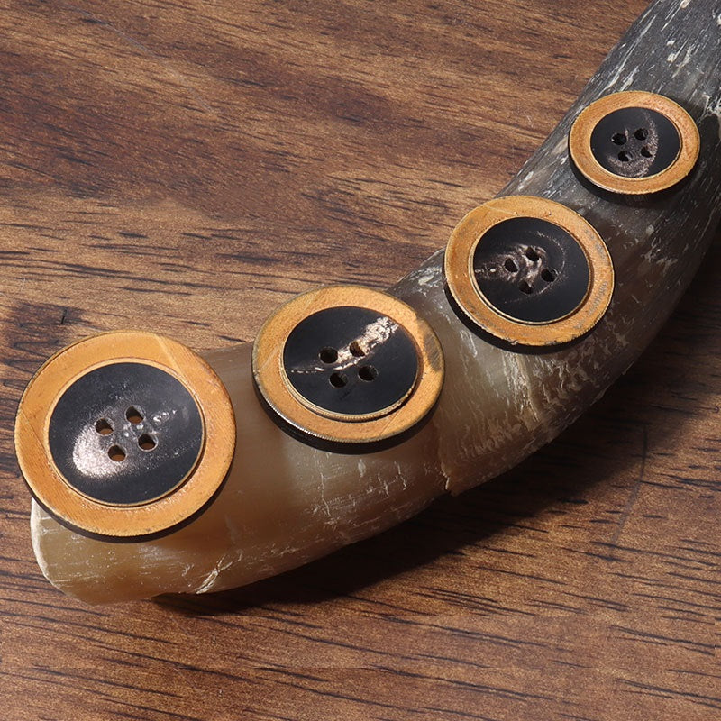 Two black four-hole round buttons with horn-look outer edge