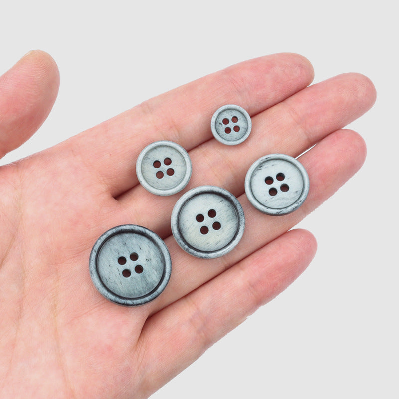 Gray 4-hole buttons in a hand, vintage natural bone style, for sweaters or coats