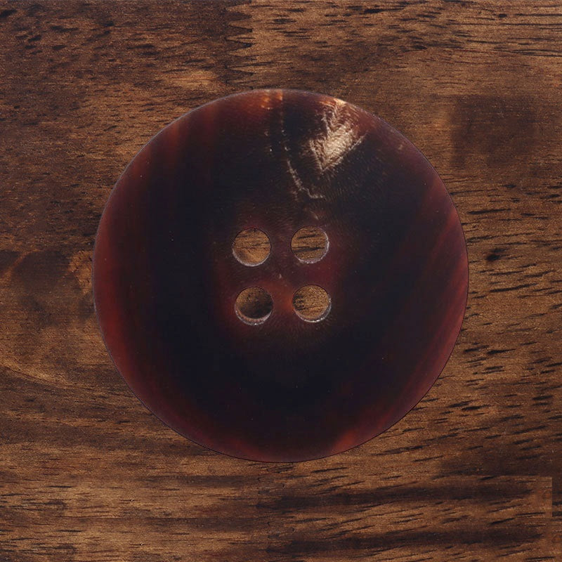 Dark navy matte round button, back view with four sewing holes