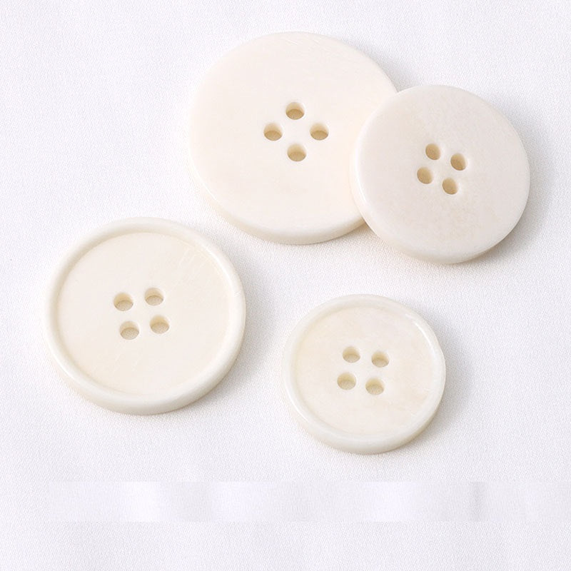 Overlapping off-white 4-hole buttons, front views showing four holes