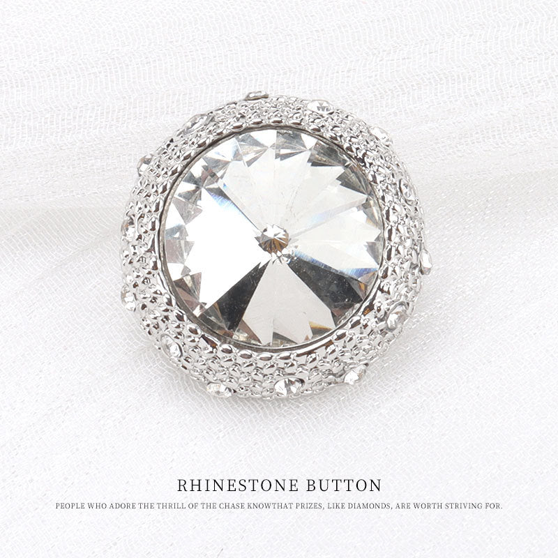 Silver round rhinestone button with large clear faceted center and ornate textured border