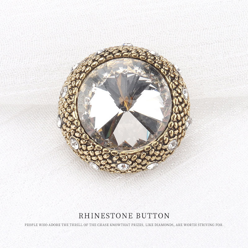 Gold round rhinestone button with clear faceted center and small rhinestone accents