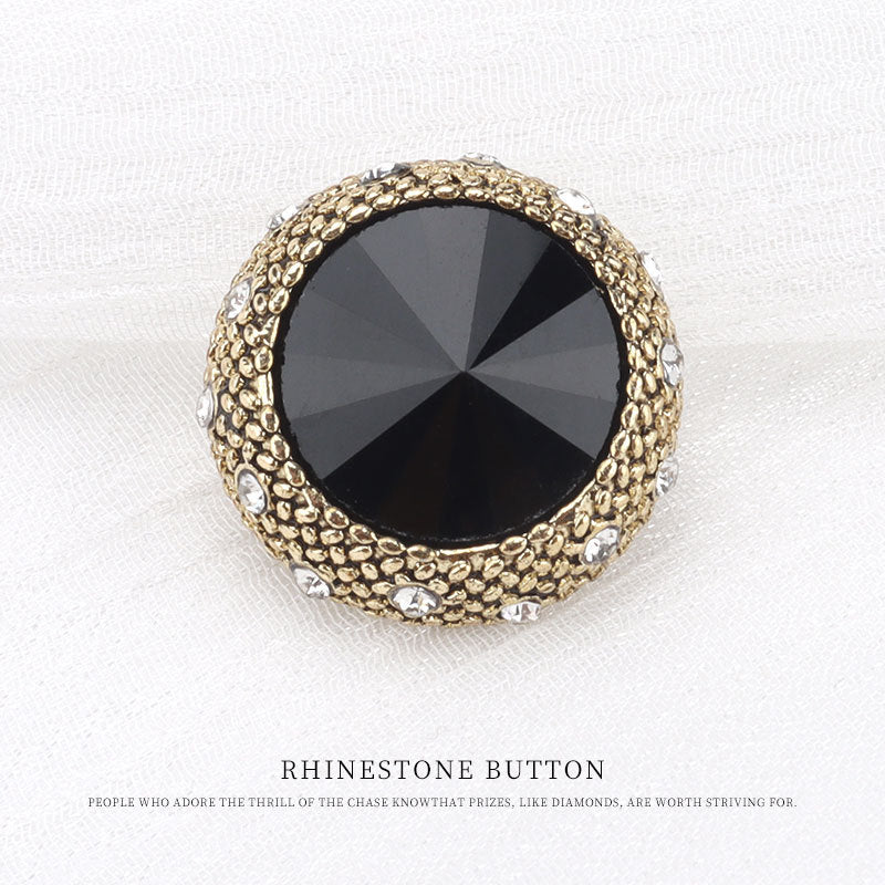 Gold round rhinestone button with black faceted center and rhinestone border accents