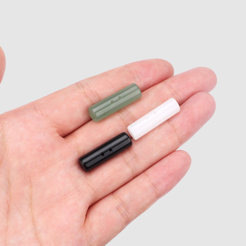 Three 25mm cylindrical two-hole buttons on a hand: light green, white, and black
