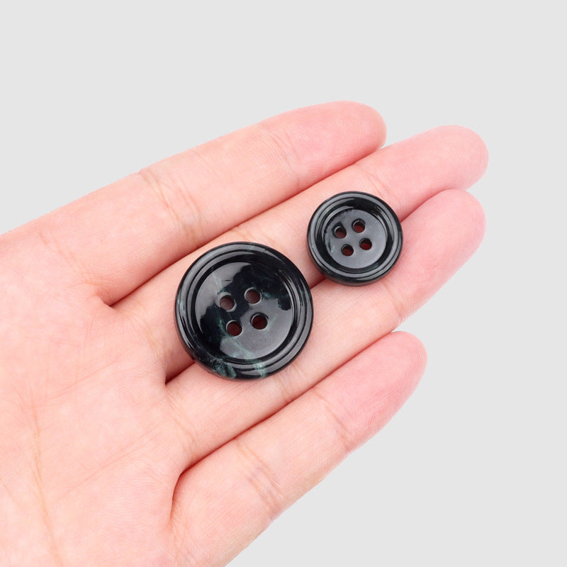 Pair of round dark green four-hole buttons, backside view