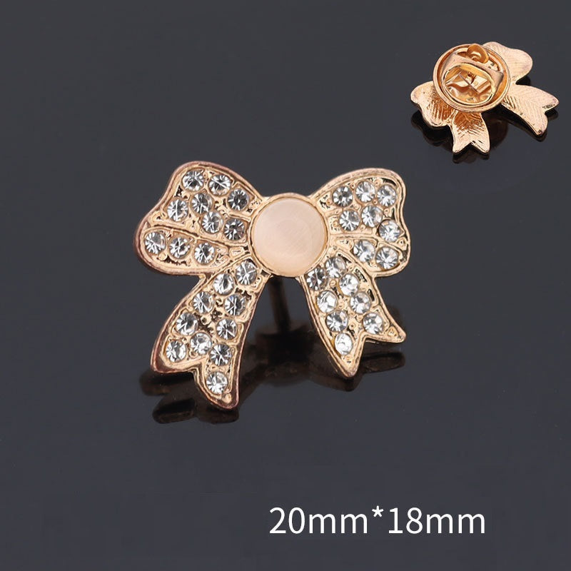 Golden bow brooch with round white pearl center and rhinestone trim, 20mmx18mm