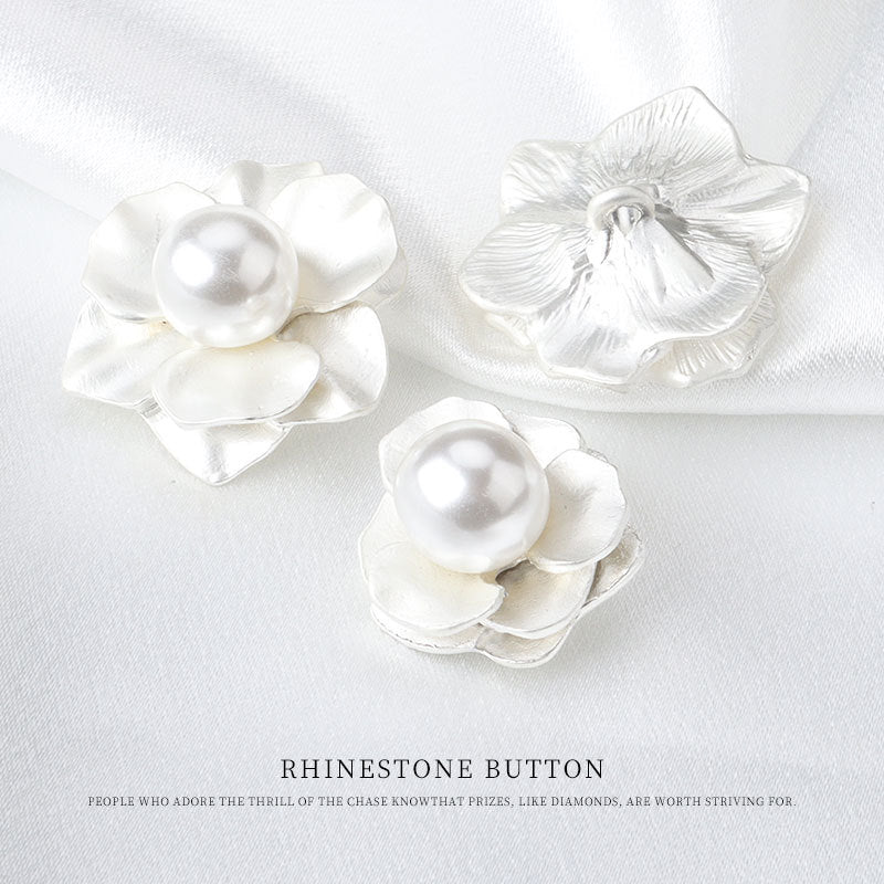 Three white flower buttons with pearl-like centers and fabric shanks
