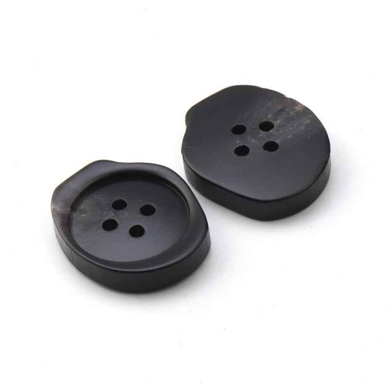 Black 4-hole resin buttons, flat round faces with scalloped backs, pair close-up