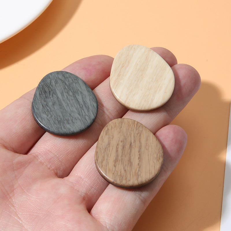 Oval resin shank buttons on hand: dark gray and light beige wood-grain faces
