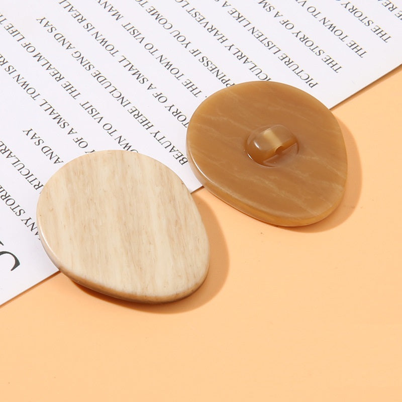 Oval resin shank button pair: light beige wood-grain face and amber-brown shank back