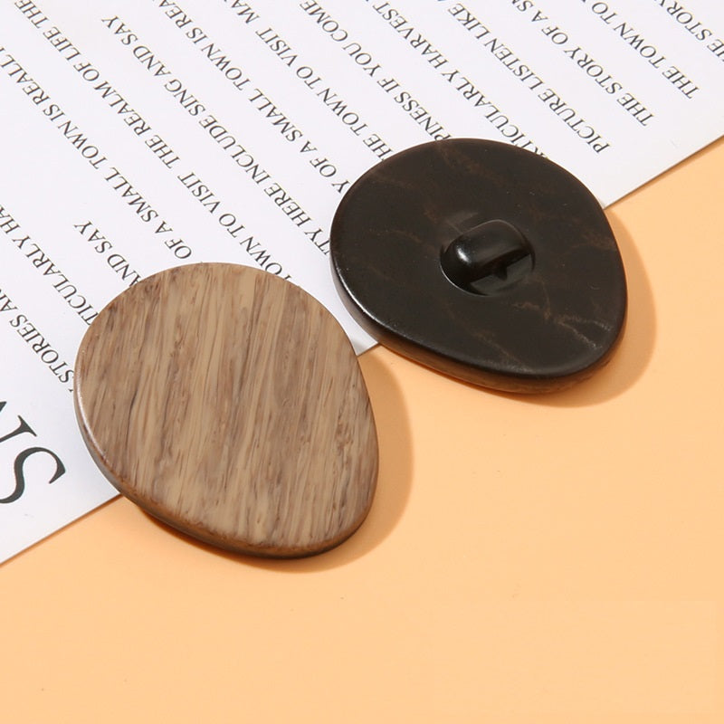 Oval wood-grain resin shank button, beige-brown face with dark back and center shank