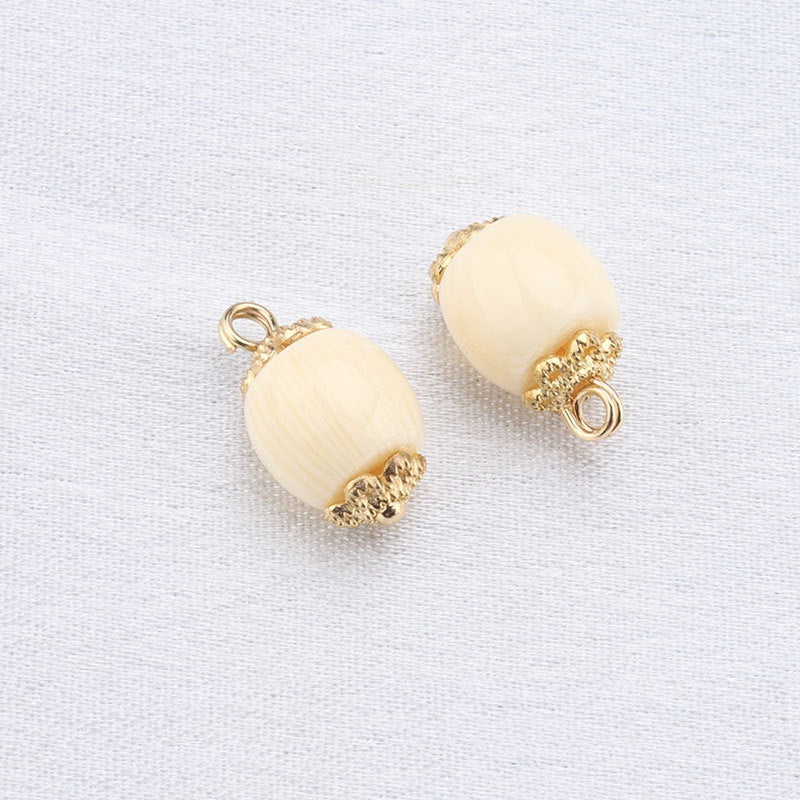 Beige oval resin frog button pair with gold textured metal top and bottom cap