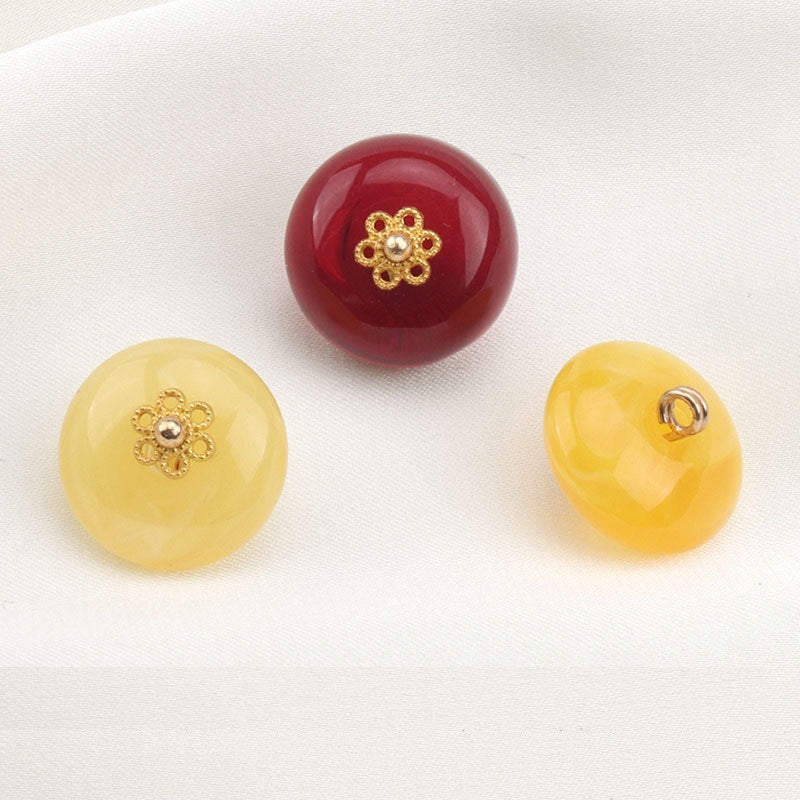 Round resin buttons: dark red and pale yellow, gold floral centers; metal loop on one